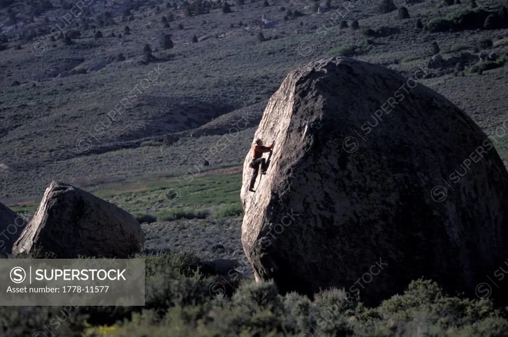 A man bouldering in the desert on a hot day