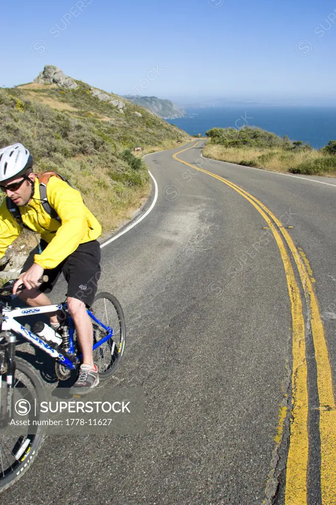 Young man biking Highway 1 near the California Coastal Trail; Golden Gate National Recreation Area San Francisco, California