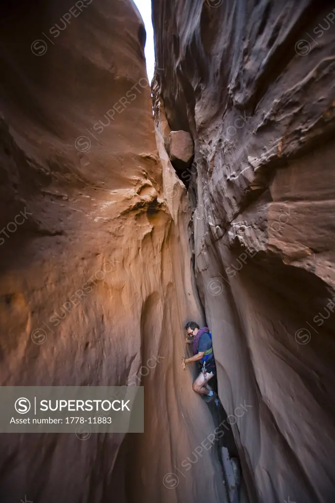 A man chimneying down a slot canyon, Utah