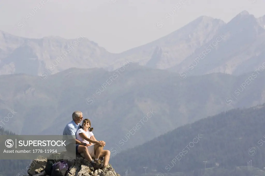 Mid-aged couple enjoy view from peak of a mountain in the Lizard Range near Fernie, British Columbia