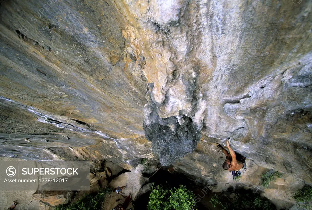 A man climbs a limestone cliff in Thailand