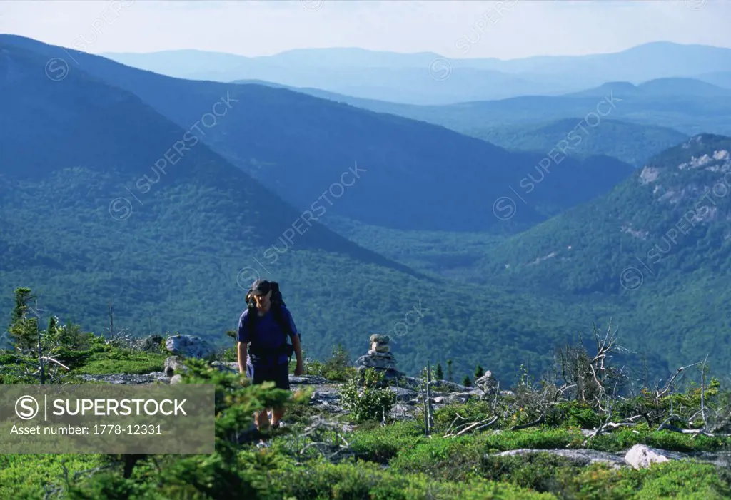 A hiker on western Maine's Grafton Loop Trail with Grafton Notch in the distance