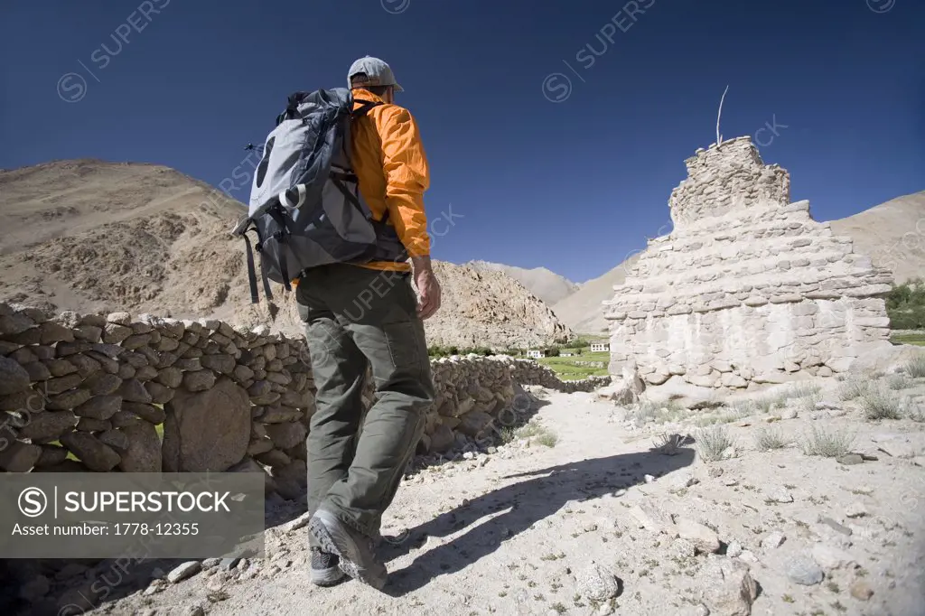 Man walks past Buddhist chorten or stupa during trek in Ladakh, India