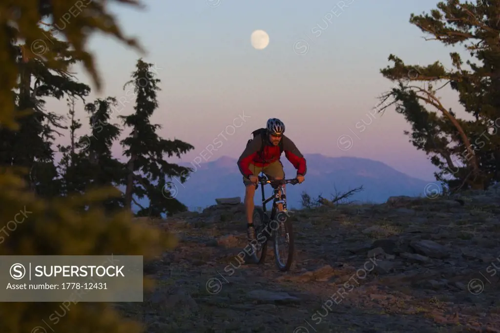 A man mountain bikes beneath the moon on the Tahoe Rim Trail in California