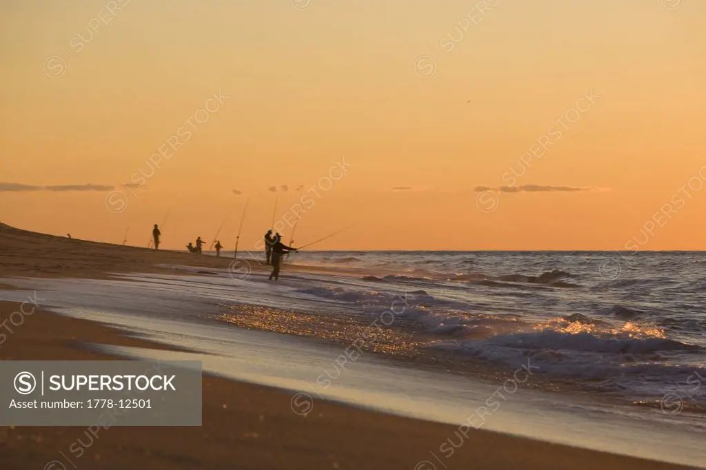 Fisherman casts from the shore at sunset on  Cape Cod National Seasohore outside of Provincetown, Massachusetts