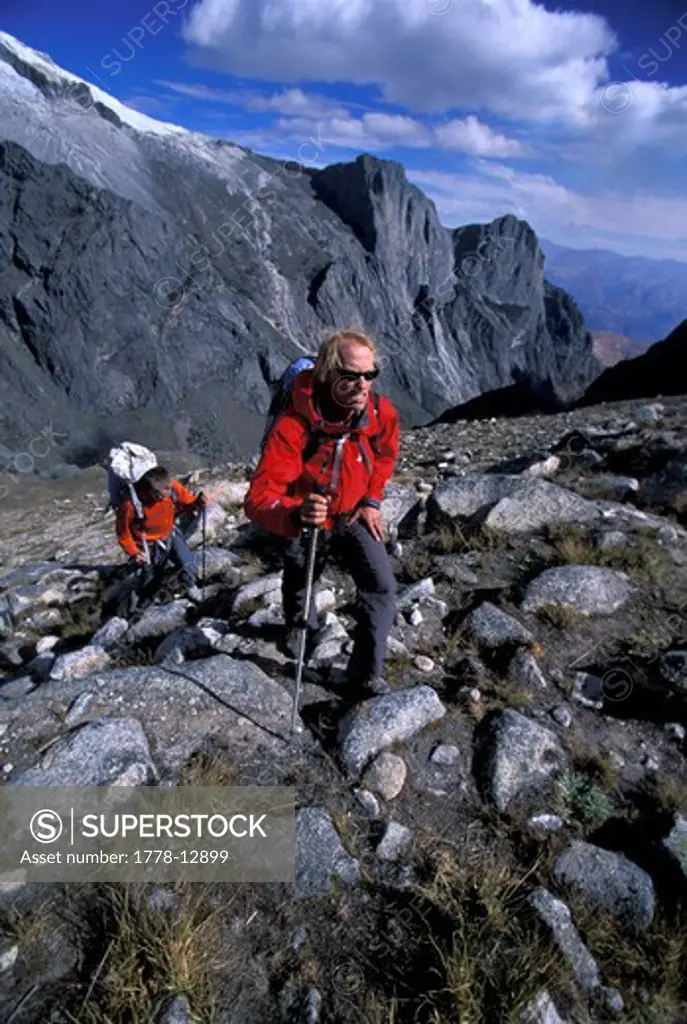 Two men hiking in the mountains with trekking poles in Cordillera Blanca, Peru
