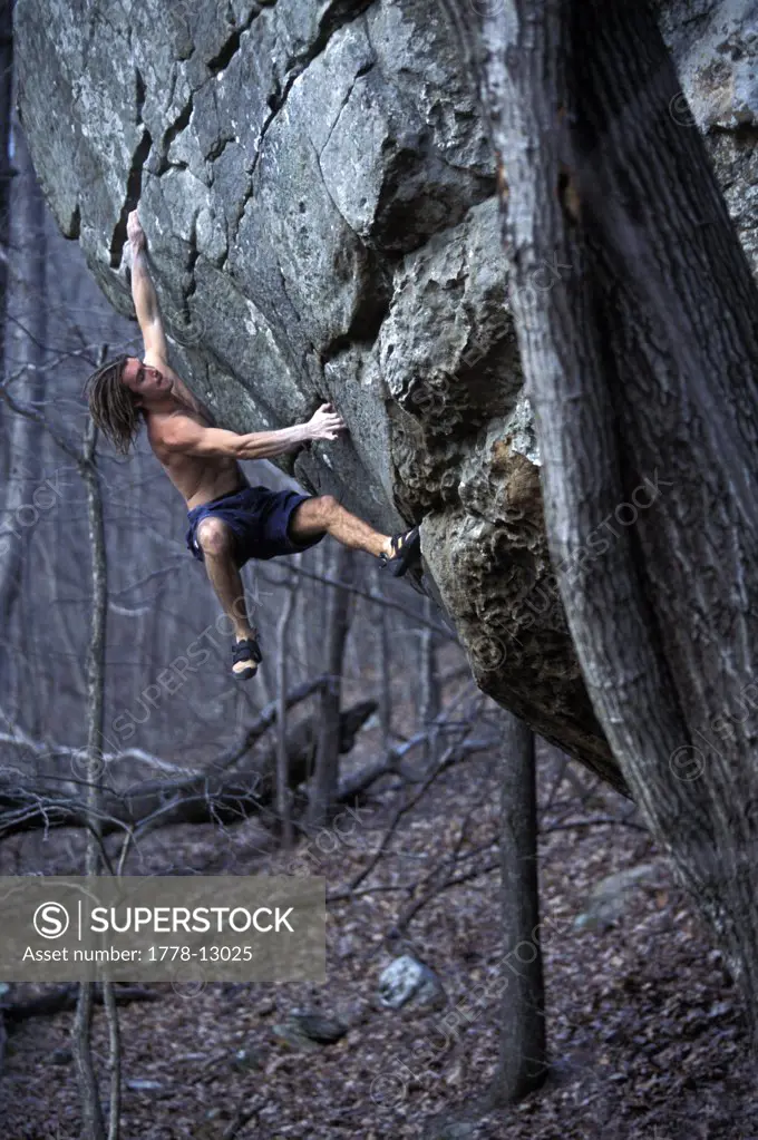 A male rock climber reaching for a hold while bouldering near Jasper, Arkansas