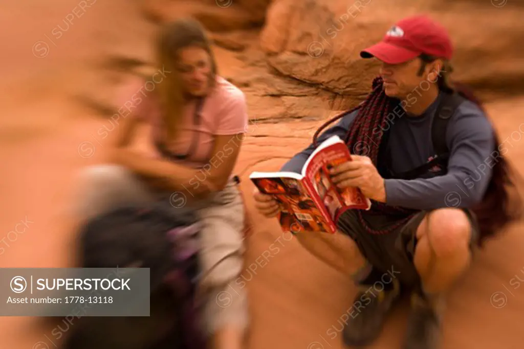 A man and woman look at a book as they explore Blue John Canyon located in southeast Utah (Selective Focus)