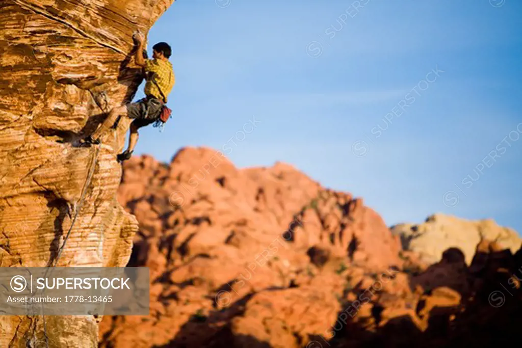 A man climbs an arete on a sandstone crag in the desert