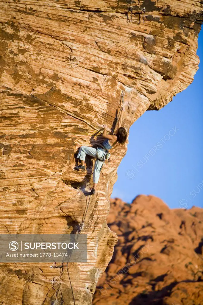 A women stretches to clip the draw on the crux while climbing