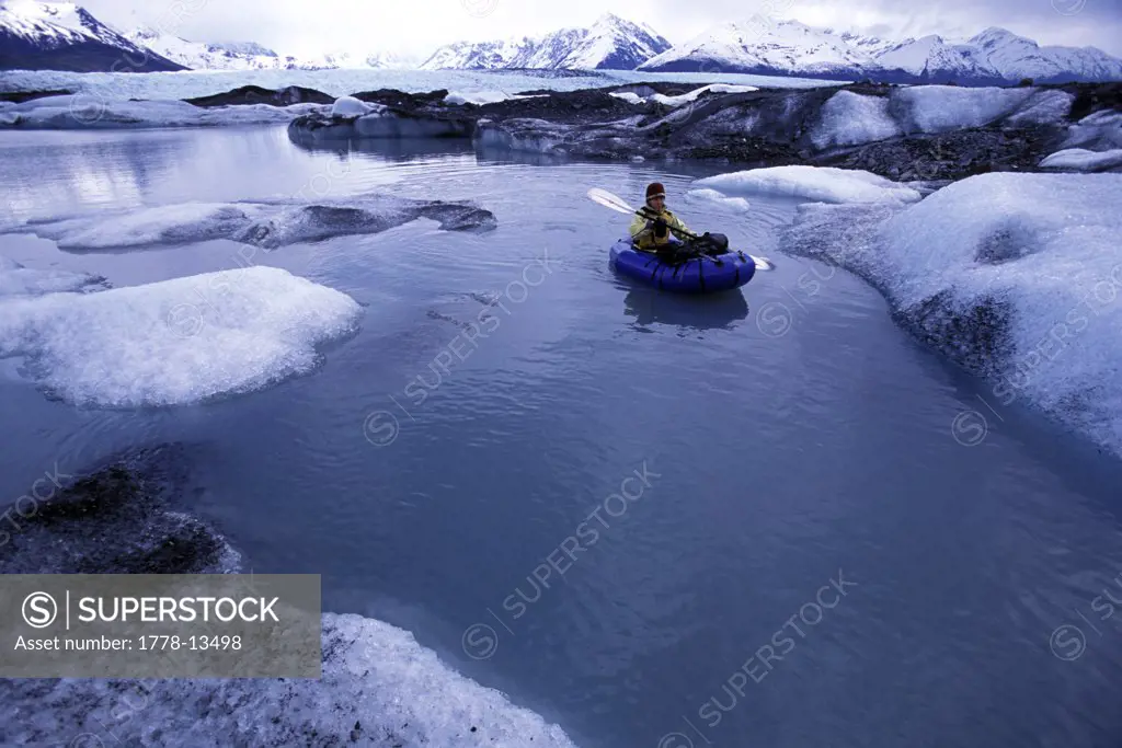 A woman pack rafting between icebergs in Knik River, Alaska