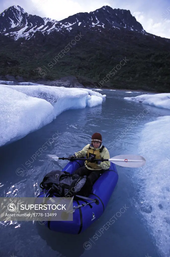A woman pack rafting between icebergs in Knik River, Alaska