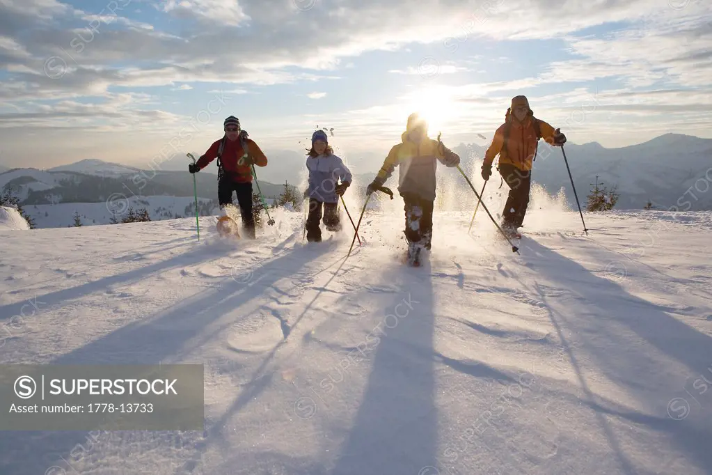 Four people snowshoeing in France (back-lit)