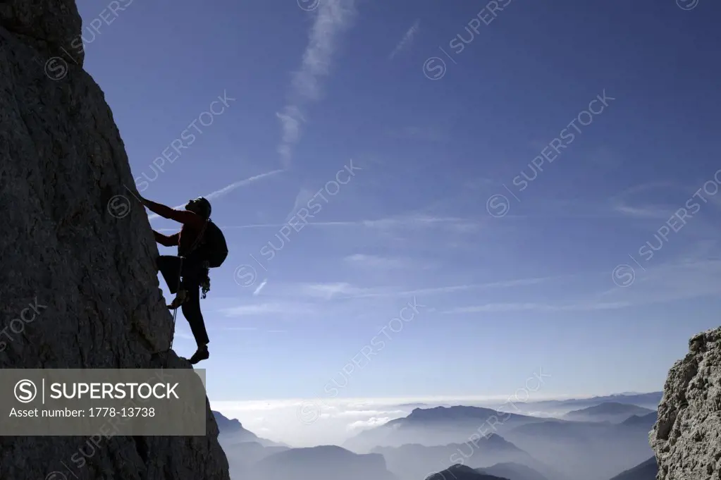 A climber on a steep cliff in Italy