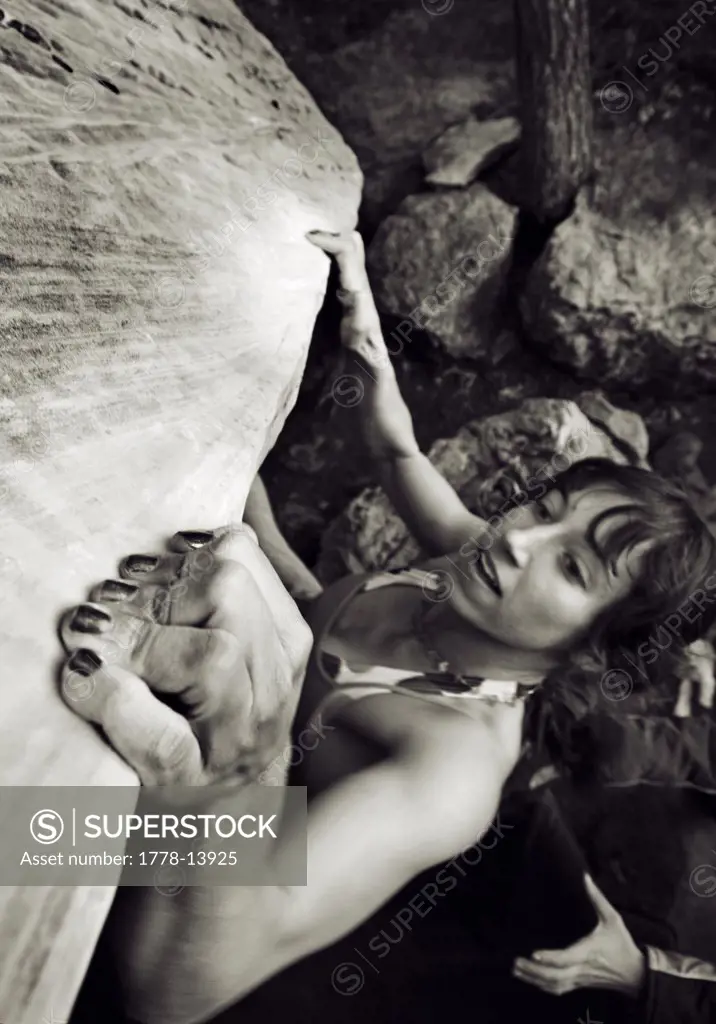 A yong woman pulls hard on a sloper hold while bouldering in Sedona, Arizona