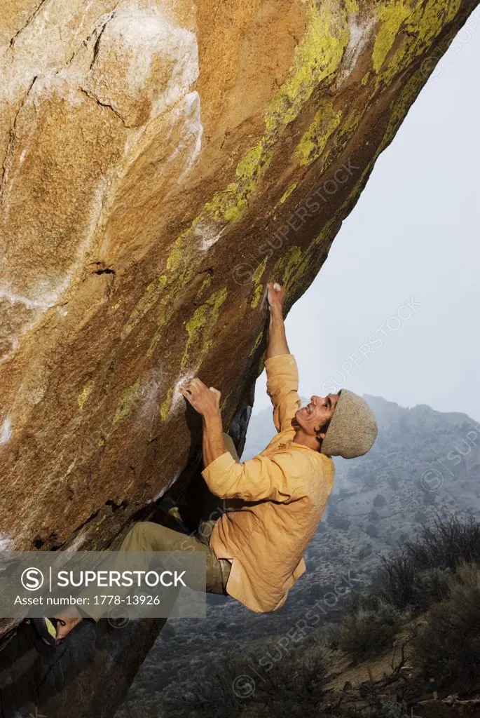 A young man pulls hard on small holds while rockclimbing at the Buttermilks near Bishop, Ca