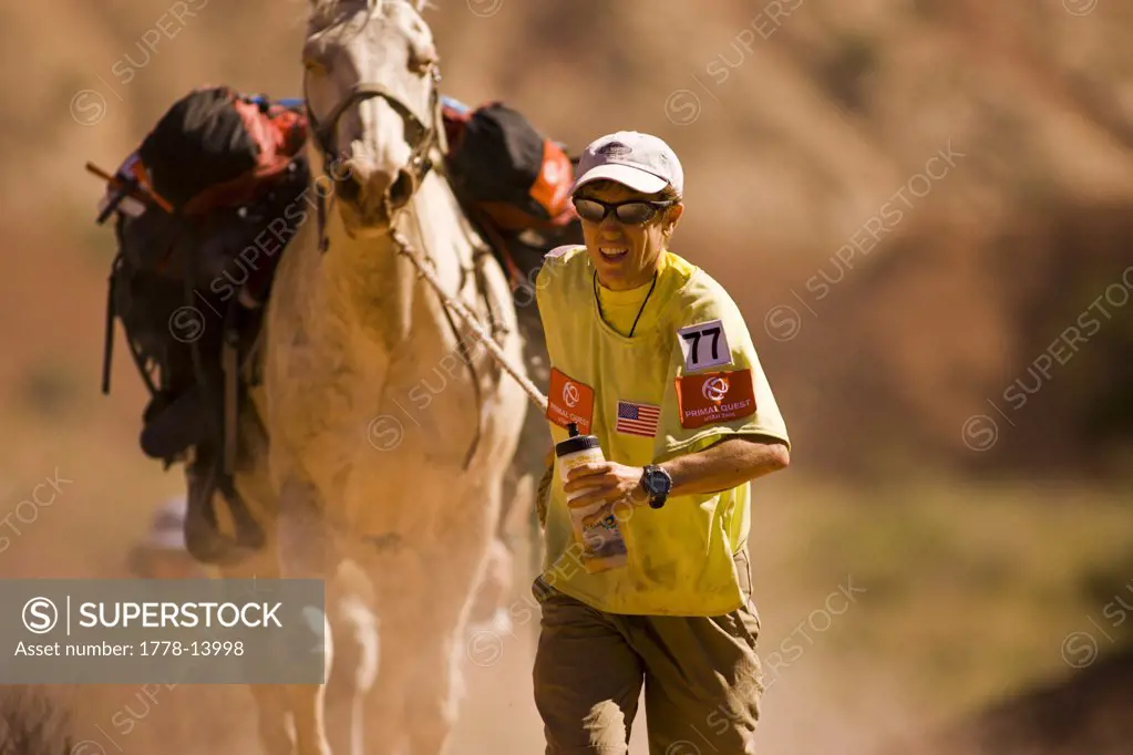 Adventure racer running and leading a horser in a race in Moab, Utah