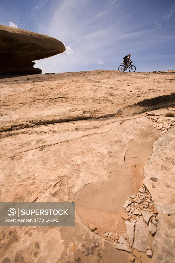 Racer mountain biking by a rock in an adventure race near Moab, Utah