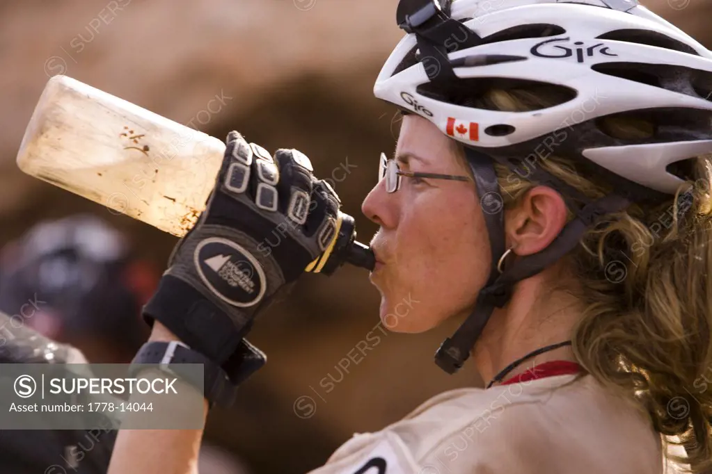Female adventure racer drinking water while mountain biking in a race in Moab, Utah