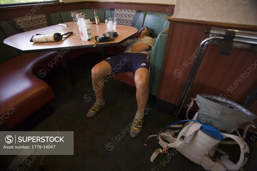 Man sleeping in a booth at a restaurant during an adventure race near Moab, Utah