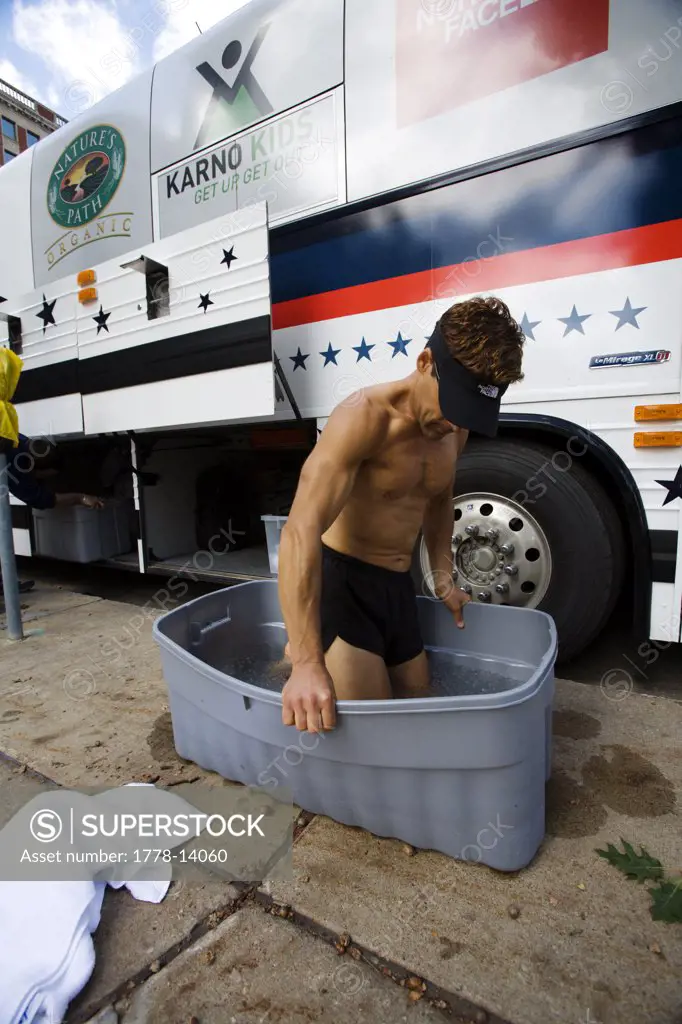 Runner soaking his legs in a tub of ice water after a marathon in Des Moines, Iowa