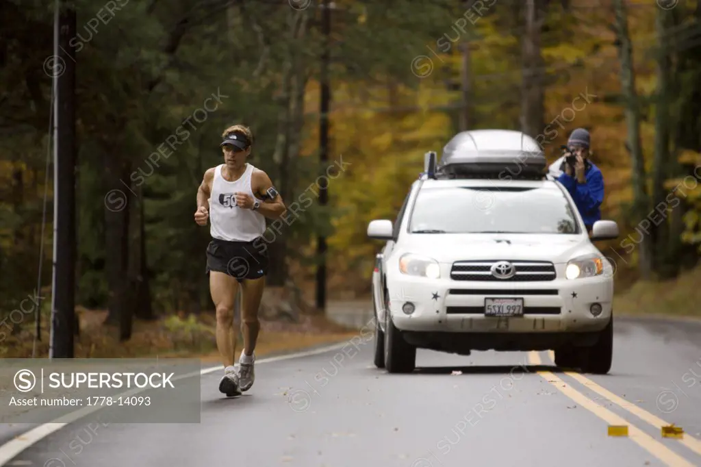 Man running a marathon and being videotaped-documented by a support car in Bristol, New Hampshire