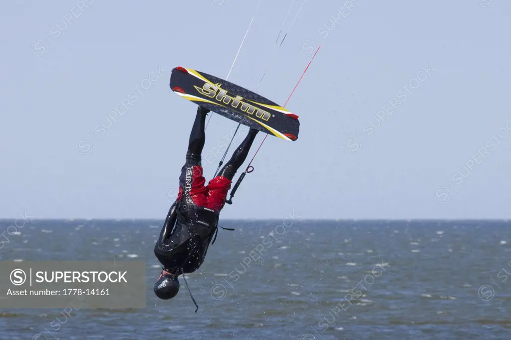 A kiteboarder hangs upside down while suspended in mid-air under his kite