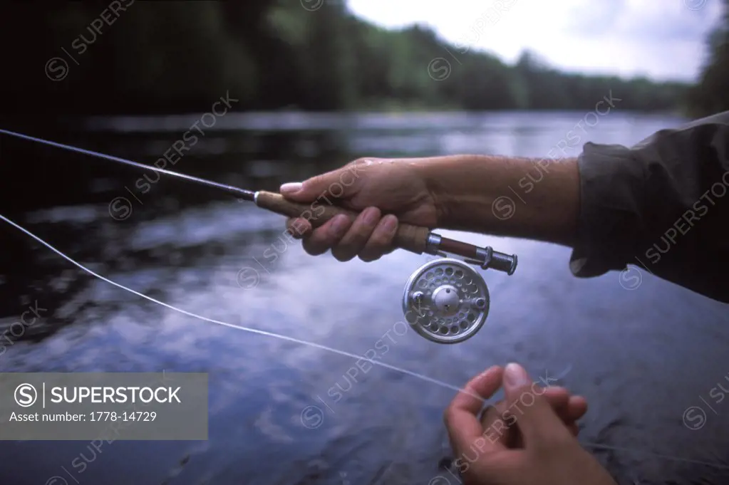 A fisherman demonstrates how he holds the line and reel while fly fishing at the east outlet of the Kennebec River near Greenvil