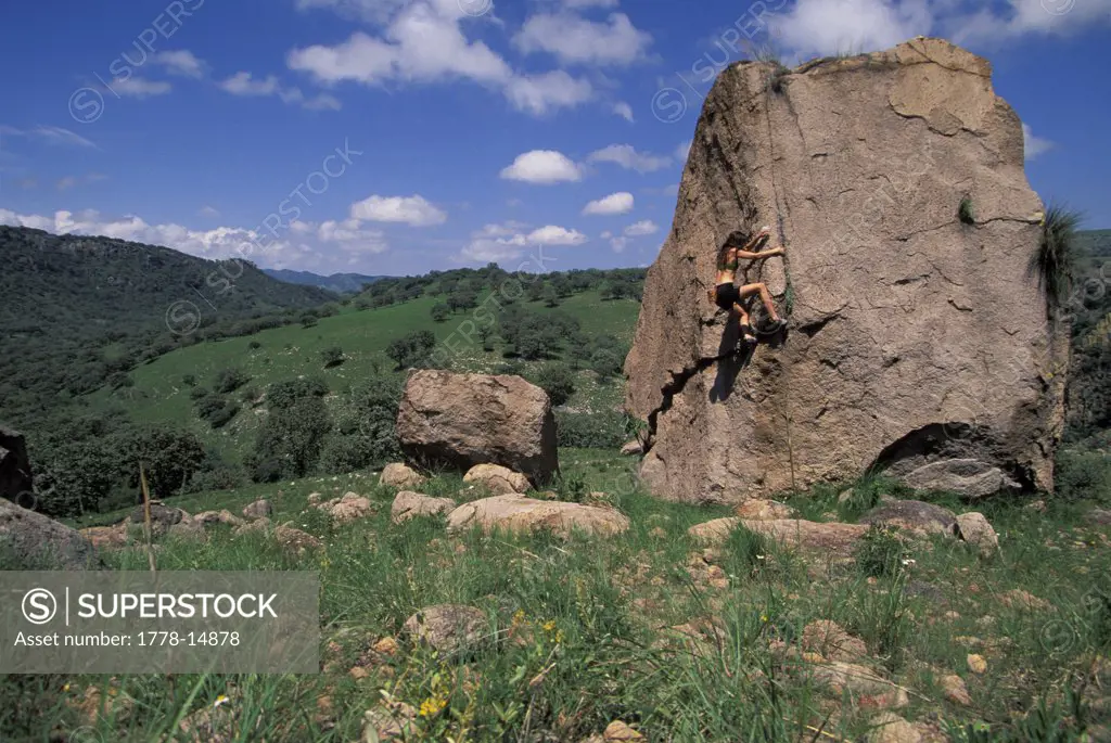 Woman bouldering in a field with blue sky