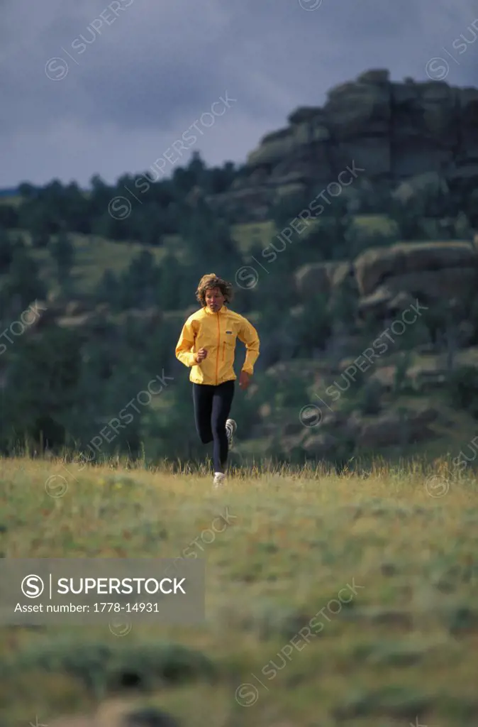 Woman trail running in green hills