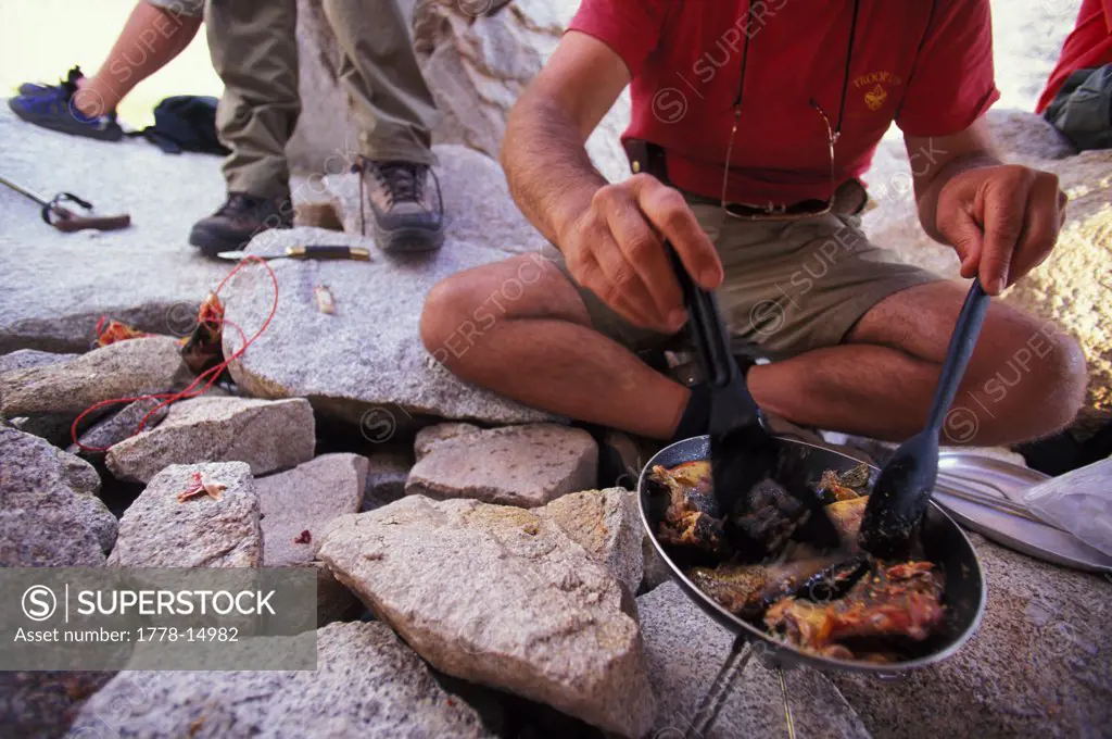 Man cooking dinner-fish on a small stove camping