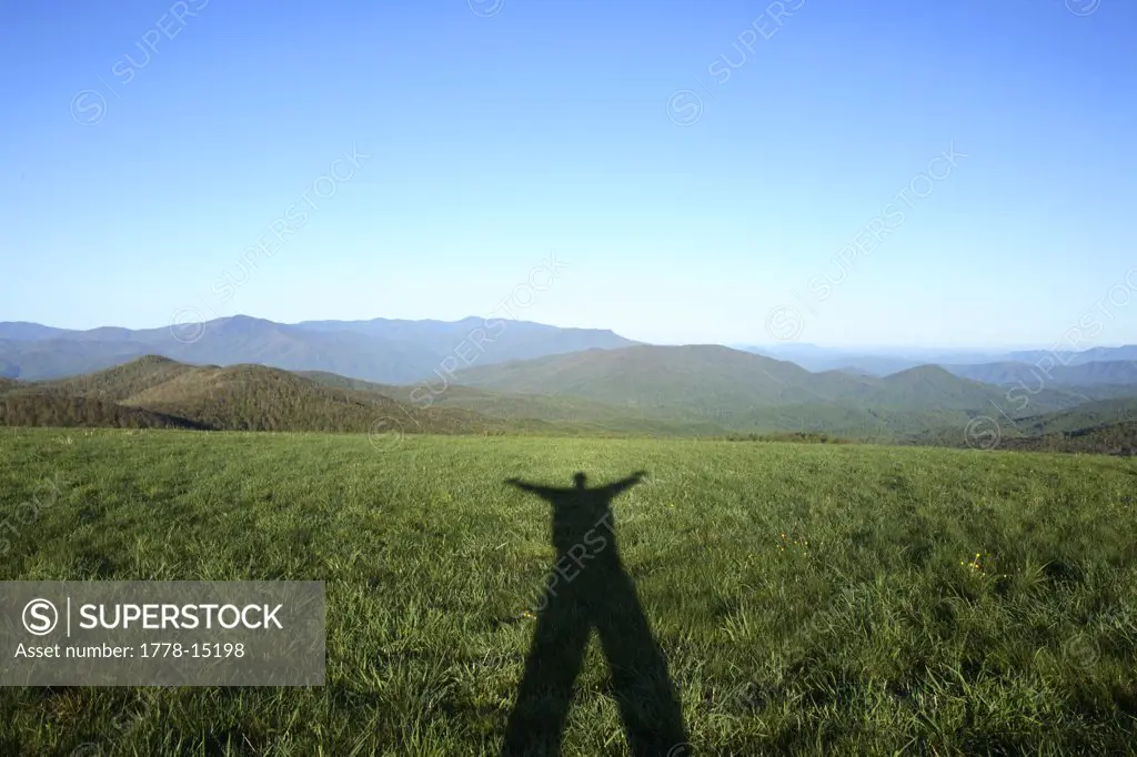 Male casts his long shadow while taking a break along the Appalachian Trail at the summit of Max Patch Bald west of Asheville, N