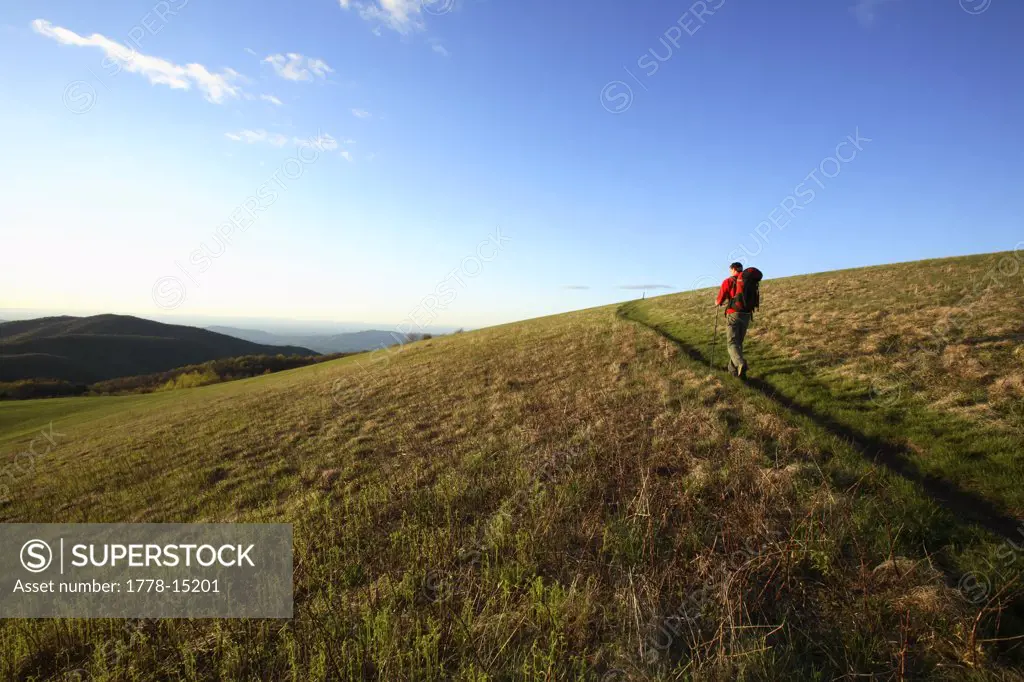 Male backpacker climbs the final stretch of the Appalachian Trail to the summit of Max Patch Bald west of Asheville, NC