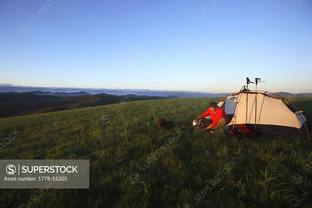 Male backpacker brews up some coffee at his tentsite along the Appalachian Trail on the summit of Max Patch Bald west of Ashevil
