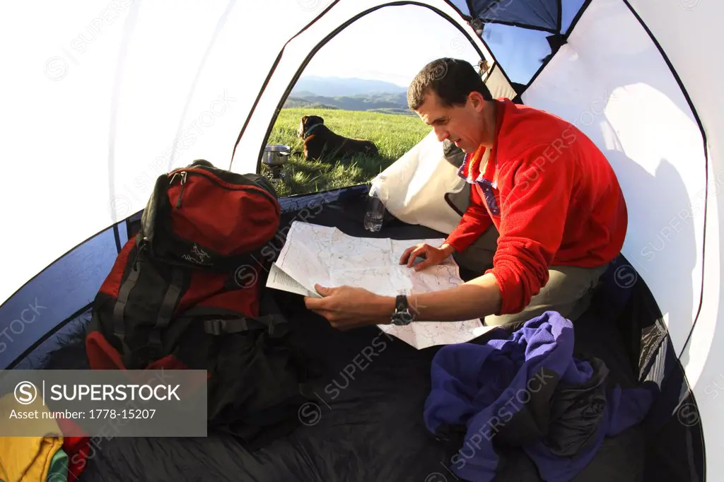 Male backpacker examines a map in his tent at camp along the Appalachian Trail on the summit of Max Patch Bald west of Asheville