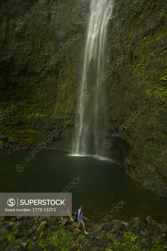 A man and a woman walk below Hanakap'ai Falls, Na Pali Coast, Kauai, Hawaii