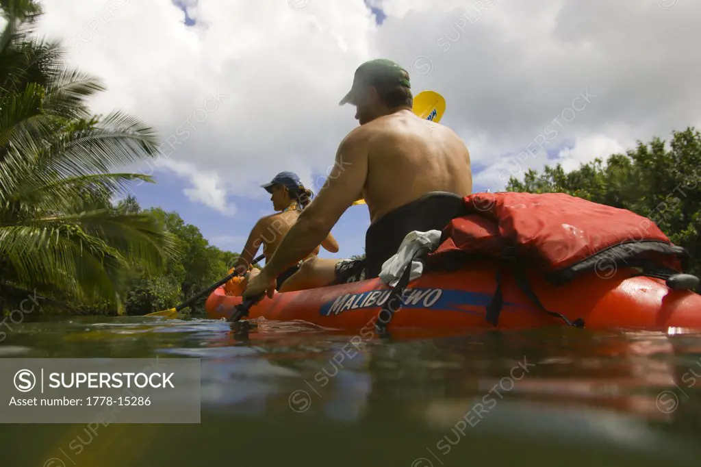 A man and a woman paddling a kayak on the Hanalei River on the Na Pali Coast, Kauai, Hawaii (water housing)