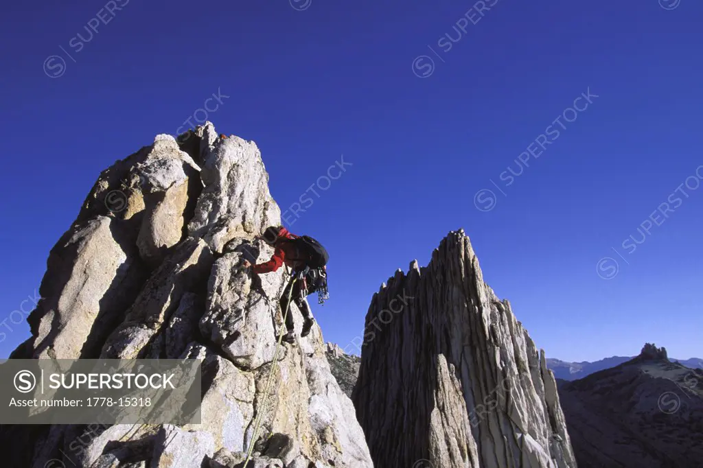 Female climber reaching the top of a mountain looking over a big valley