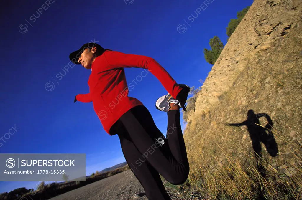 Attractive female runner stretching in tights with nice light