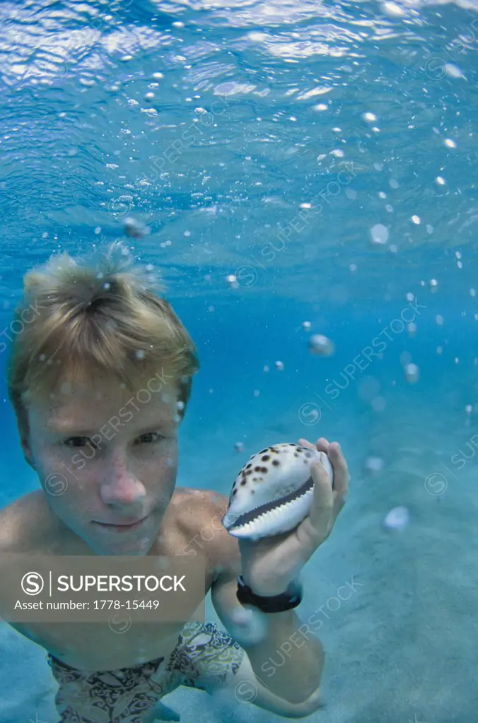 Boy with shell, underwater, Hawaii