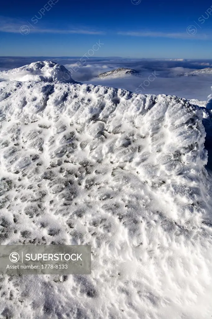 The rocky, snow covered terrain on Mt Washington in the White Mountains of New Hampshire beneath a clear blue sky