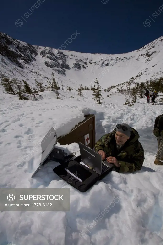 A member of the National Guard sets up a laptop with a satellite dish to transmit Inferno race times to the bottom of the course at Pinckham Notch