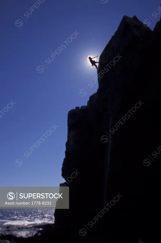 Climber rappelling off ocean cliff