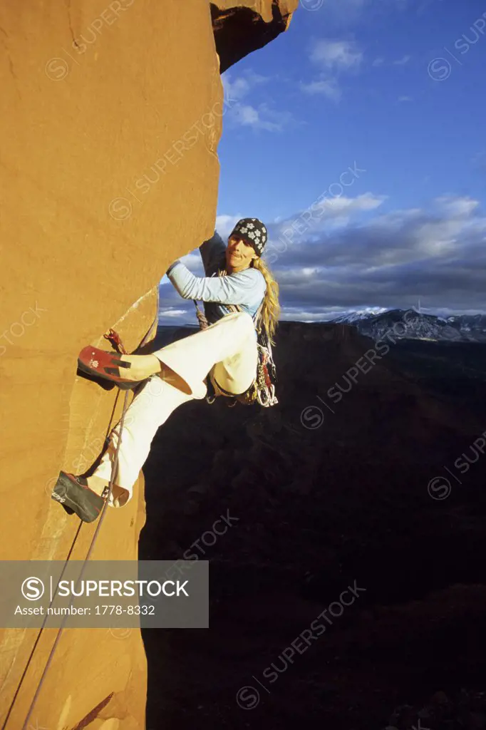 A woman rock climber moving up a sandstone tower in Castle Valley, Utah (blurred motion)