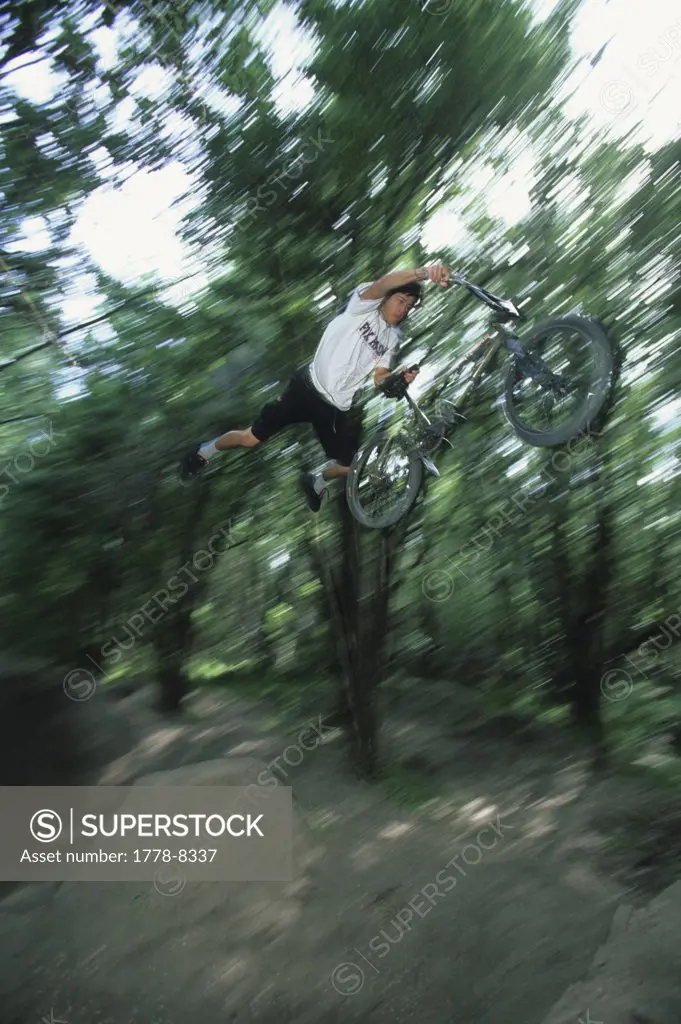 Man jumping his BMX bike in the forest, Utah