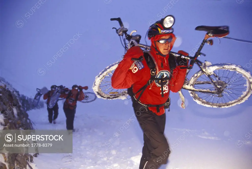 Man carrying mountian bike in the snow during adventure race in Switzerland (Nokia branding, flash effects)