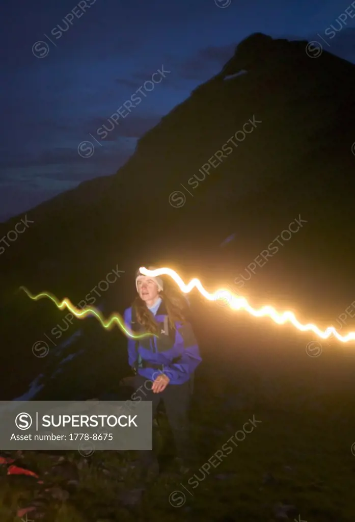 Female hiker hiking at night with a headlamp at 12,000 feet near Willow Lake in the Maroon Bells - Snowmass Wilderness near Aspe