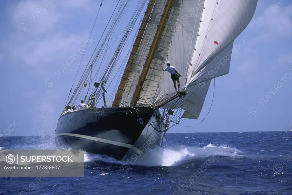 Man on bowsprit of wooden yacht