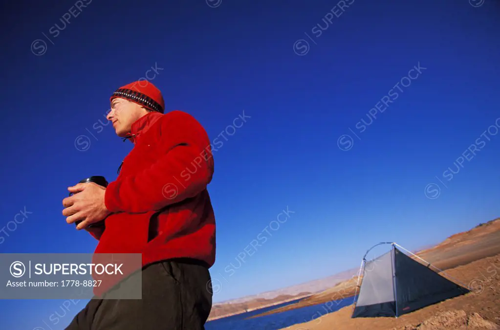 A man drinks coffee outside tent