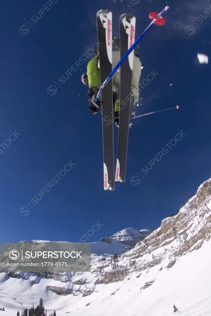 Man jumping over camera on skis with mountains behind